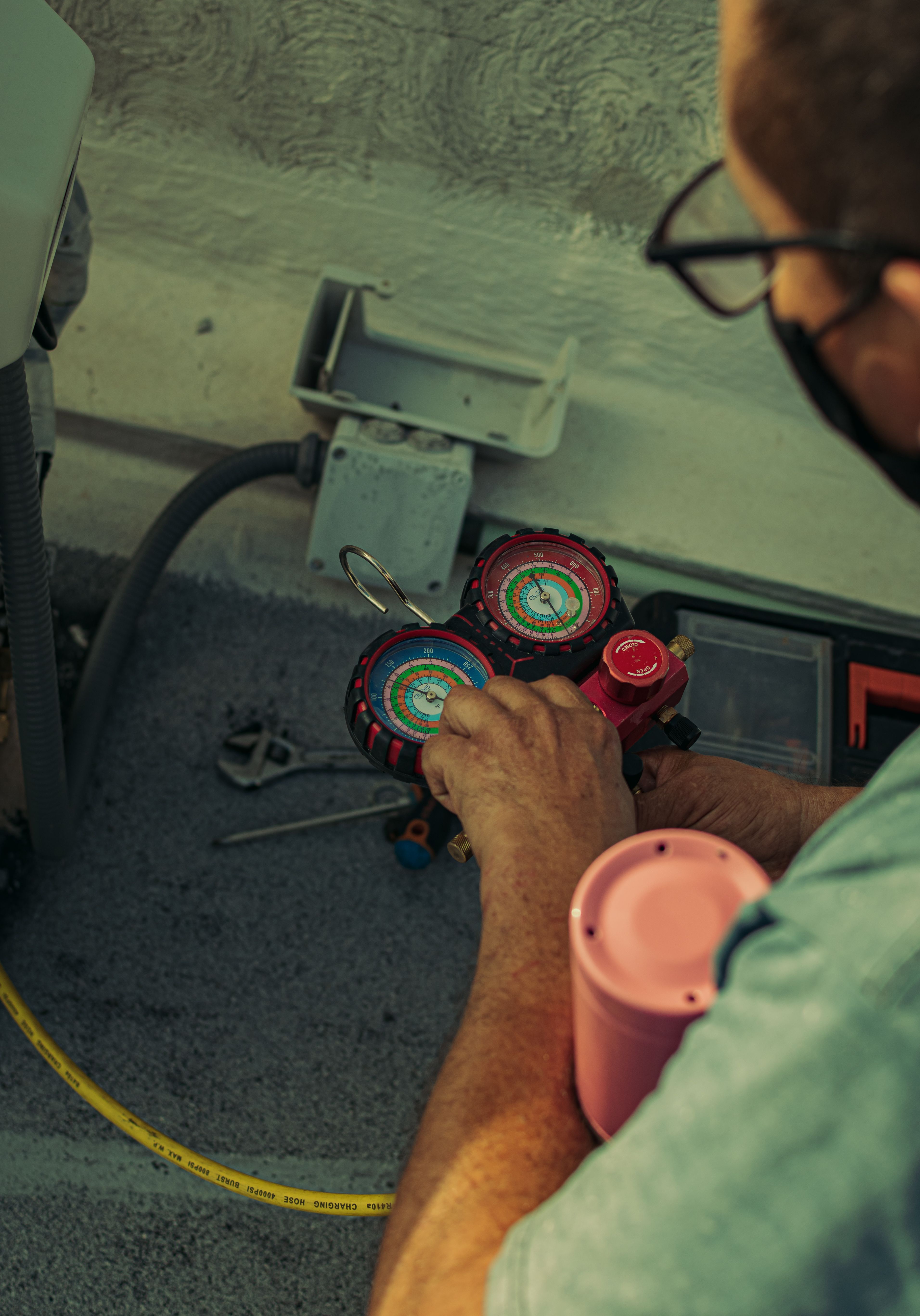 A Circle City HVAC technician checking refrigerant pressure on an AC system with manifold gauges.